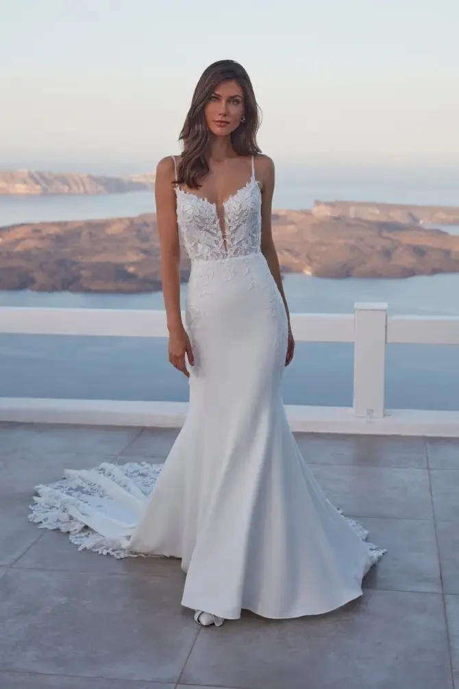 model is wearing a sleeveless sheath wedding gown