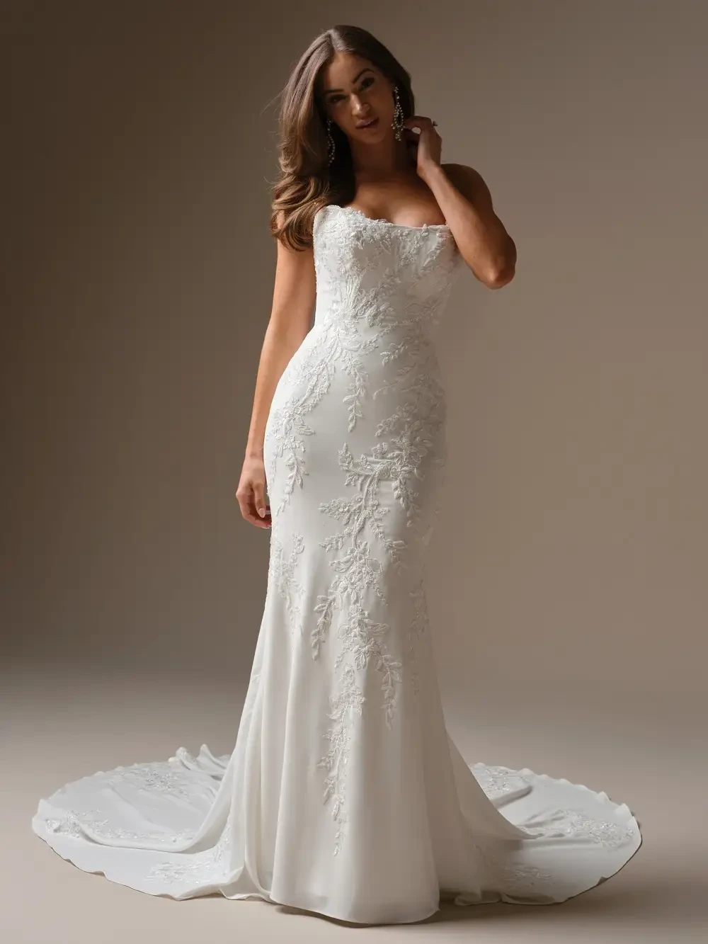 A model wearing a elegant white wedding gown with intricate embroidery, posing against a neutral background.